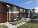 The apartment building features a brown exterior, red doors, and a staircase leading to the upper level units at 1909 Caralee Blvd # 4, Orlando, FL 32822