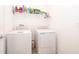 Clean laundry room with white washer and dryer set and a wire shelf, offering practicality and organization at 1920 Perch Hammock Loop, Groveland, FL 34736