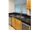 A view of the kitchen sink, stainless steel dishwasher, and black countertops and wooden cabinets at 2025 Dixie Belle Dr # 2025 B, Orlando, FL 32812