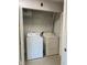 This is a laundry closet with white washer and dryer featuring storage shelves above appliances at 2025 Dixie Belle Dr # 2025 B, Orlando, FL 32812