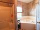 Bathroom featuring a walk in shower and soaking tub with tile walls and wooden floors at 214 Great Yarmouth Ct, Kissimmee, FL 34758