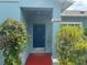 A charming blue front door with elegant details, framed by lush greenery and a red porch at 214 Great Yarmouth Ct, Kissimmee, FL 34758