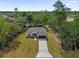 An aerial view of a modern home showcasing the large front yard, long driveway, and surrounding trees at 2483 Sw 163Rd Pl, Ocala, FL 34473