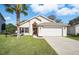 Charming single-story home featuring a well-manicured lawn, two-car garage, and inviting entryway with decorative touches at 2614 Brookshire Ct, Kissimmee, FL 34746