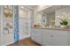 Well-lit bathroom with double vanity, contemporary mirrors, and a shower with a decorative blue patterned curtain at 2984 Moulin Rd, Davenport, FL 33837