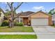 Charming single-story home with a well-manicured lawn, mature tree, and attached two-car garage at 3038 Woolridge Dr, Orlando, FL 32837