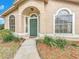 Exterior view of a home featuring a striking green front door, arched windows and well-maintained landscaping at 310 Sunvista Ct, Sanford, FL 32773