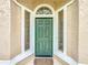 Close-up of a green front door flanked by sidelights and arched windows, creating an inviting entrance at 310 Sunvista Ct, Sanford, FL 32773