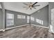 Bedroom with wood-look tile flooring, gray walls, large windows, and a ceiling fan at 3664 Sickle St, Orlando, FL 32812