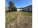 Open backyard featuring a manicured lawn, mature landscaping, and a secure white fence at 622 Samuel Pl, Davenport, FL 33837