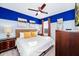 Bright bedroom featuring a king bed, blue and white walls, ceiling fan, and warm accents at 7587 Oakmoss Loop, Davenport, FL 33837