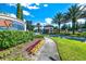 Well landscaped entrance to a beautiful community under a vibrant blue sky with palm trees at 7587 Oakmoss Loop, Davenport, FL 33837