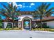 Arched entryway to a recreation center framed by palm trees and manicured flowerbeds under a blue sky at 7587 Oakmoss Loop, Davenport, FL 33837