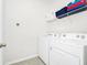 Bright laundry room features a washer and dryer with storage shelf at 7587 Oakmoss Loop, Davenport, FL 33837