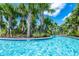 Beautiful lazy river featuring clear blue water and island landscaping with lush palm trees against a sunny blue sky at 7587 Oakmoss Loop, Davenport, FL 33837