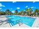 A large swimming pool with clear blue water, surrounded by palm trees and lounge chairs for relaxation at 7587 Oakmoss Loop, Davenport, FL 33837