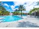 An inviting pool with a waterslide, rock features and lounge chairs surrounded by verdant palms and bright sun at 7587 Oakmoss Loop, Davenport, FL 33837