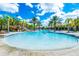 Large community pool featuring clear, refreshing water, palm trees, lounge chairs, and poolside amenities at 7587 Oakmoss Loop, Davenport, FL 33837