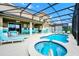 Screened-in pool and hot tub are adjacent to the covered patio seating and outdoor kitchen at 7587 Oakmoss Loop, Davenport, FL 33837