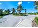 A community entrance featuring mature palm trees and manicured landscaping and flower beds at 7587 Oakmoss Loop, Davenport, FL 33837