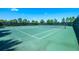 Community tennis court with new green surface surrounded by tall trees and dark green fence at 7587 Oakmoss Loop, Davenport, FL 33837