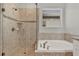 Bright bathroom featuring a bathtub and glass-enclosed shower with neutral toned tile and a mosaic accent at 8330 Vivaro Isle Way, Windermere, FL 34786