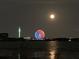 Colorful Ferris wheel and tower reflecting on the water with the moon in the sky at night at 8814 Southern Breeze Dr, Orlando, FL 32836