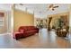 Spacious living room with a red couch and a ceiling fan, with the kitchen visible at 117 Cupania Ct, Groveland, FL 34736