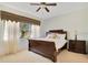 Well-lit bedroom boasts neutral walls, carpet, and a large window with curtains at 117 Cupania Ct, Groveland, FL 34736