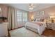 Cozy bedroom with a ceiling fan, two windows, and a cream-colored bed set on a hardwood floor at 11735 Whitewing Ct # 11735, Orlando, FL 32837