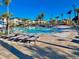 Resort-style pool with palm trees, lounge chairs, and modern buildings under a sunny sky at 1304 Sea Pines Way, Davenport, FL 33896