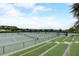 View of multiple fenced tennis courts with lush green landscape surrounding the community amenity at 1304 Sea Pines Way, Davenport, FL 33896