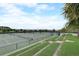 View of multiple fenced tennis courts with lush green landscape surrounding the community amenity at 1304 Sea Pines Way, Davenport, FL 33896