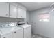 Functional laundry room equipped with modern white appliances, ample storage cabinets, and a window at 134 E Plantation Blvd, Lake Mary, FL 32746