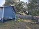 Backyard featuring a blue house, a wheelbarrow, and lush trees beyond a wooden fence at 1404 High St, Leesburg, FL 34748