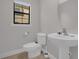 Simple powder room featuring a pedestal sink, white toilet, and neutral finishes at 14530 Damai Ln, Orlando, FL 32821