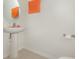 Minimalist powder room featuring a pedestal sink, light beige flooring, and a bright orange towel at 2029 Crystal Bell St, Orlando, FL 32824