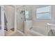 Bright bathroom features a combined tub and shower with glass doors, and tiled walls at 3455 Bellingham Dr, Orlando, FL 32825