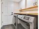 Laundry room with white cabinets, wood countertop, slate tile floor, and modern washer and dryer at 5276 Rocking Horse Pl, Oviedo, FL 32765