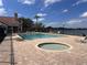 Outdoor pool and hot tub area with brick patio and lounge chairs overlooks a serene lake at 7213 Greenville Ct, Orlando, FL 32819