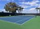 Outdoor tennis court with green and blue playing surfaces, net, and seating area at 7213 Greenville Ct, Orlando, FL 32819