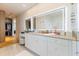 Elegant bathroom with double vanity, lighted mirrors, white cabinetry and a walk-in closet at 9138 Bay Point Dr, Orlando, FL 32819