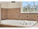 Close up of bathtub with tile surround and large window providing natural light at 105 Norris Pl, Casselberry, FL 32707