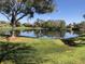 Scenic pond reflecting the sky, surrounded by lush green grass and mature trees on a sunny day at 1080 Abell Cir, Oviedo, FL 32765