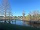 Scenic view of a tranquil pond from the property, with beautiful foliage and a clear blue sky at 10800 Cherry Oak Cir, Orlando, FL 32817