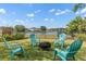 Backyard seating area with pond view, fire pit, blue Adirondack chairs, and manicured lawn at 12621 Oulton Cir, Orlando, FL 32832