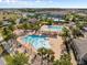 A stunning aerial view of the community pool, featuring a splash pad, covered seating, and plenty of lounge chairs and palm trees at 12621 Oulton Cir, Orlando, FL 32832