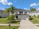 Two-story home featuring a manicured lawn, a two-car garage, and palm trees in the front yard at 12621 Oulton Cir, Orlando, FL 32832