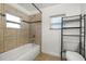 Bathroom featuring tile, shower-tub combo, storage rack, and a bright window at 1622 Dolphin Dr, St Cloud, FL 34771
