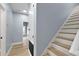 Hallway with light wood floors leading to the stairs and additional rooms, showcasing natural light and neutral paint at 2073 Home Again Rd, Apopka, FL 32712